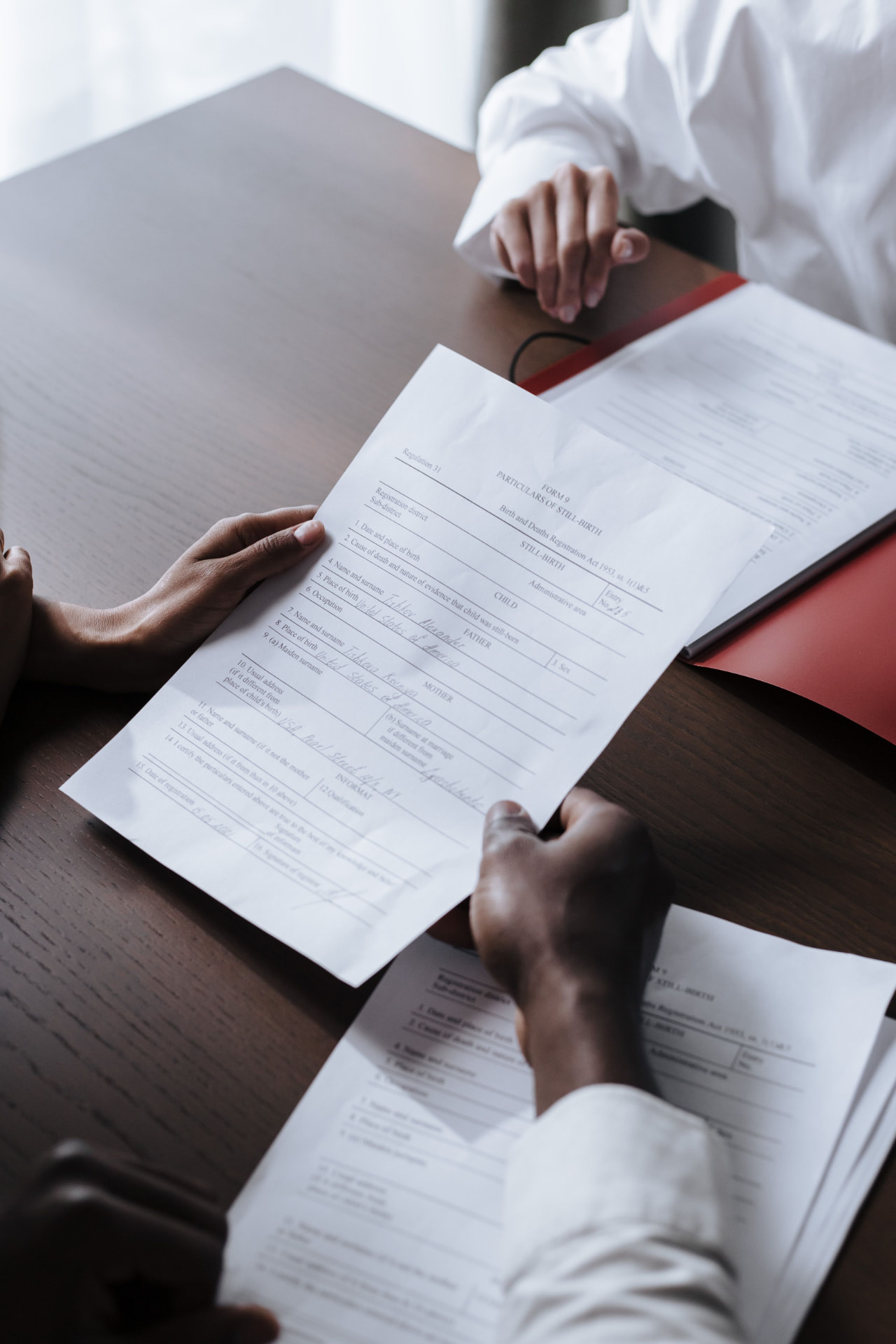 Hands exchanging an official document across a desk